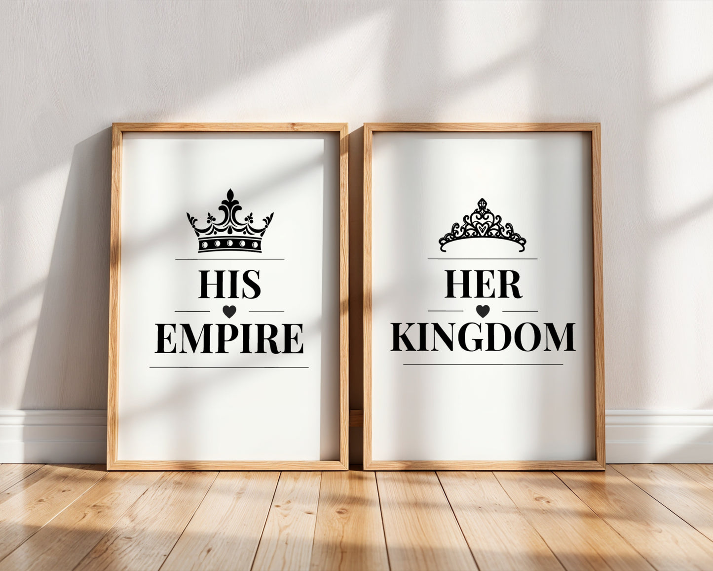 Two framed art prints leaning against a white wall on a wooden floor. The left print says 'HIS EMPIRE' with a black crown graphic, and the right print says 'HER KINGDOM' with a black tiara graphic.