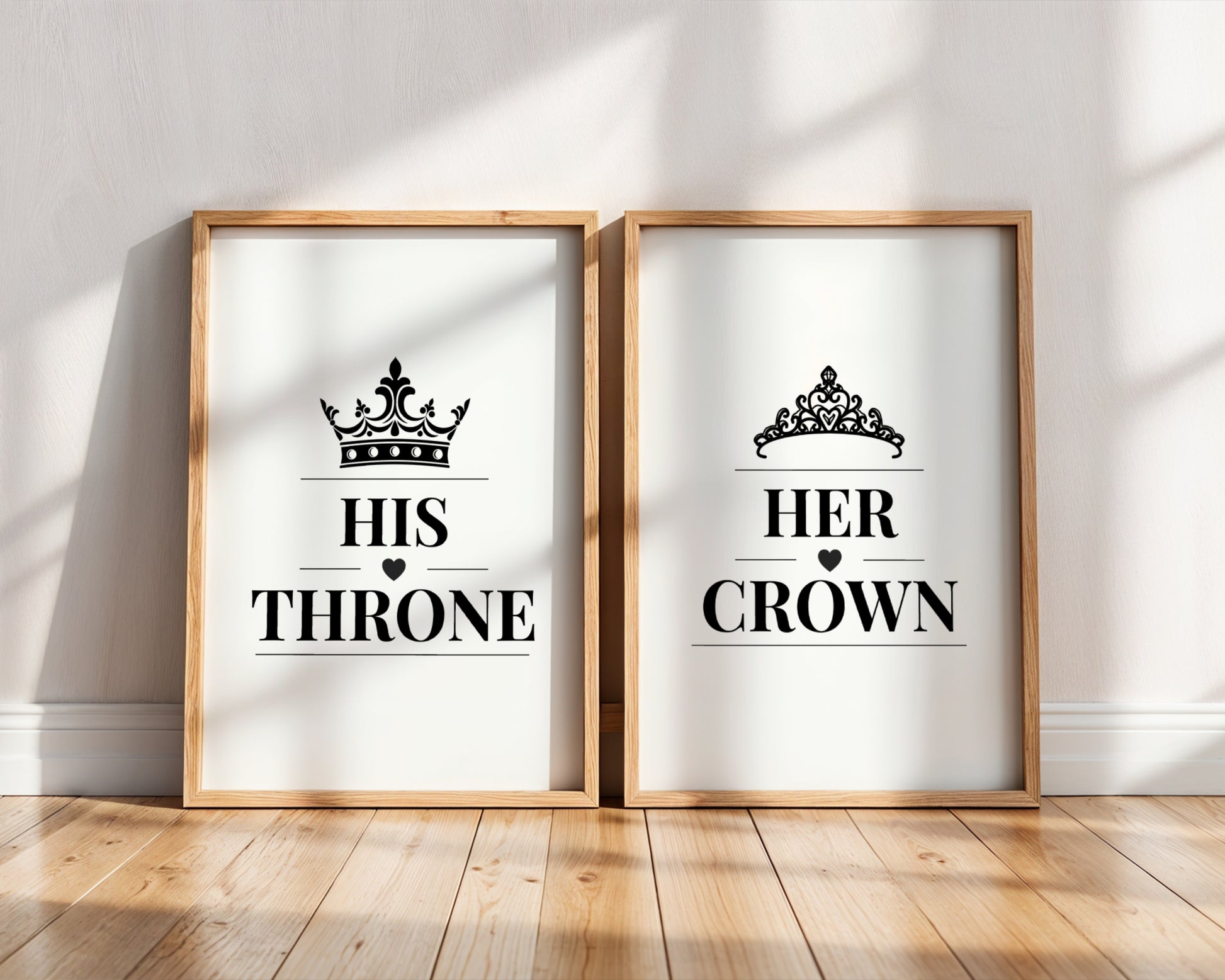 Two framed wall art prints leaning against a white wall on a wood floor. The left print says "HIS THRONE" with a black crown above, and the right print says "HER CROWN" with a black tiara above.