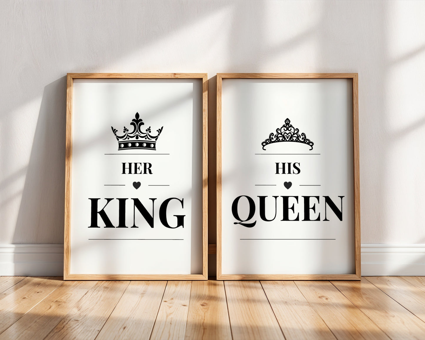 Two framed minimalist wall art prints leaning against a white wall on a light wood floor. The left print says 'HER KING' with a black crown above, and the right print says 'HIS QUEEN' with a black tiara above.