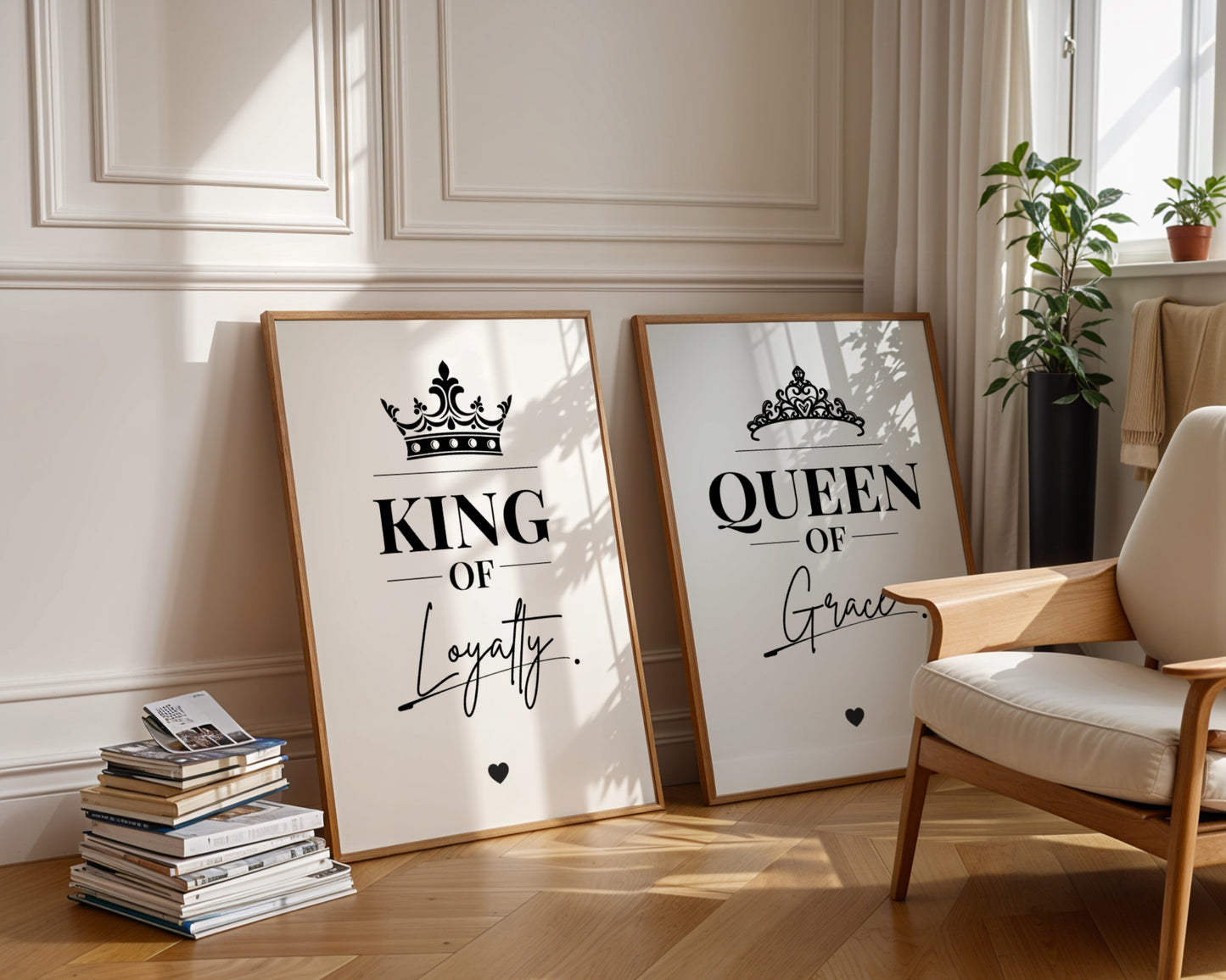 Two framed motivational wall art prints leaning against a cream paneled wall in a styled room. The left print says 'KING OF Loyalty' with a crown graphic, and the right print says 'QUEEN OF Grace' with a tiara graphic.