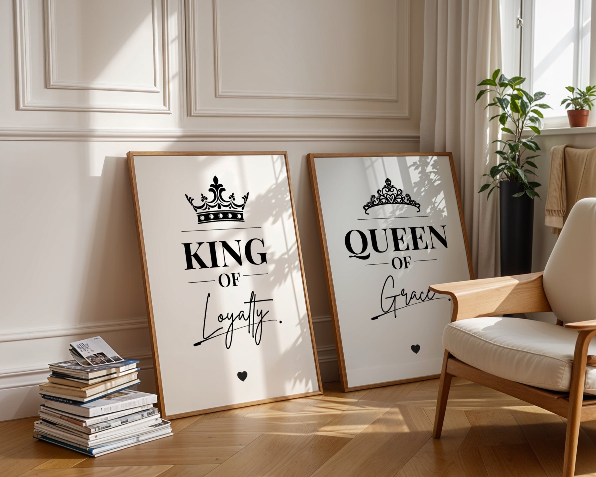 Two framed motivational wall art prints leaning against a cream paneled wall in a styled room. The left print says 'KING OF Loyalty' with a crown graphic, and the right print says 'QUEEN OF Grace' with a tiara graphic.