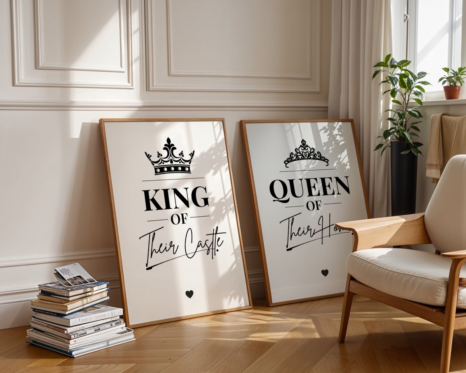 Two framed wall art prints leaning against a cream paneled wall in a sunlit room. The left print says "KING Of Their Castle" with a crown graphic, and the right print says "QUEEN Of Their Home" with a tiara graphic.