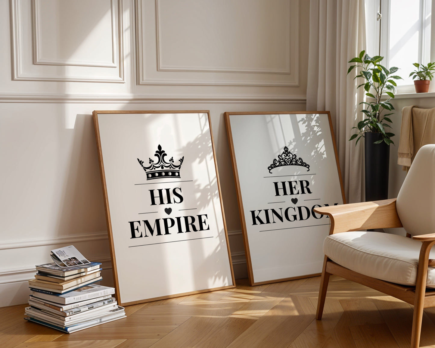 Two framed art prints leaning against a cream paneled wall on a wooden floor, styled in a bright living room next to a wooden armchair and potted plants. The left print reads 'HIS EMPIRE' with a crown graphic, and the right print reads 'HER KINGDOM' with a tiara graphic.