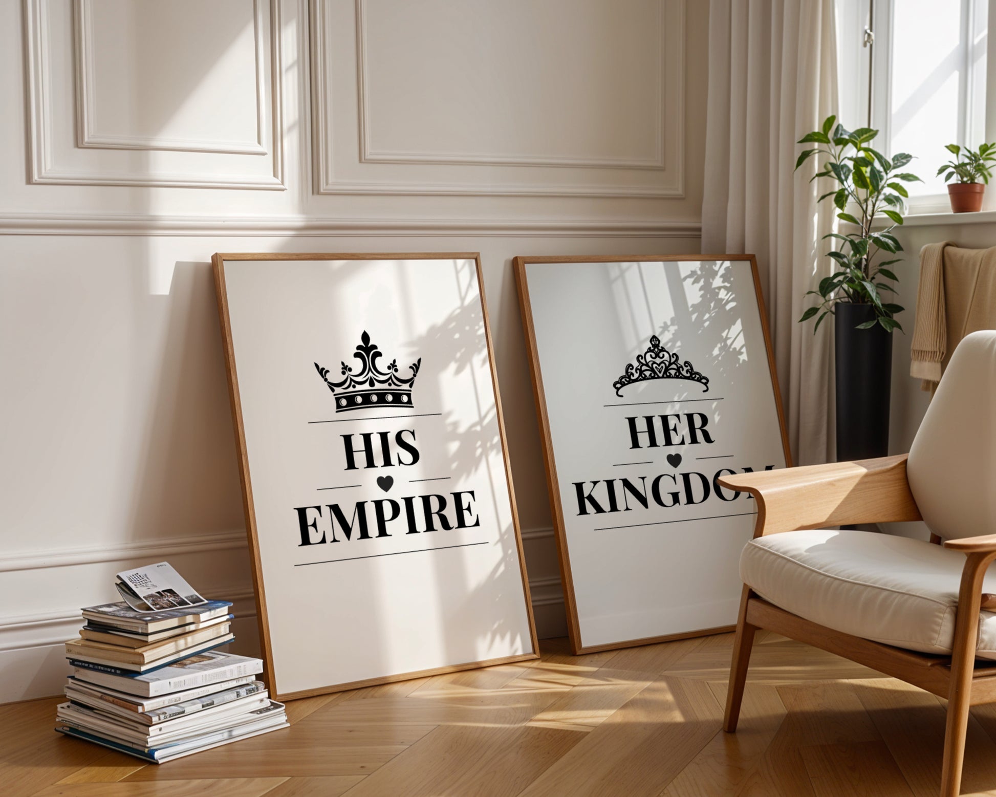 Two framed art prints leaning against a cream paneled wall on a wooden floor, styled in a bright living room next to a wooden armchair and potted plants. The left print reads 'HIS EMPIRE' with a crown graphic, and the right print reads 'HER KINGDOM' with a tiara graphic.
