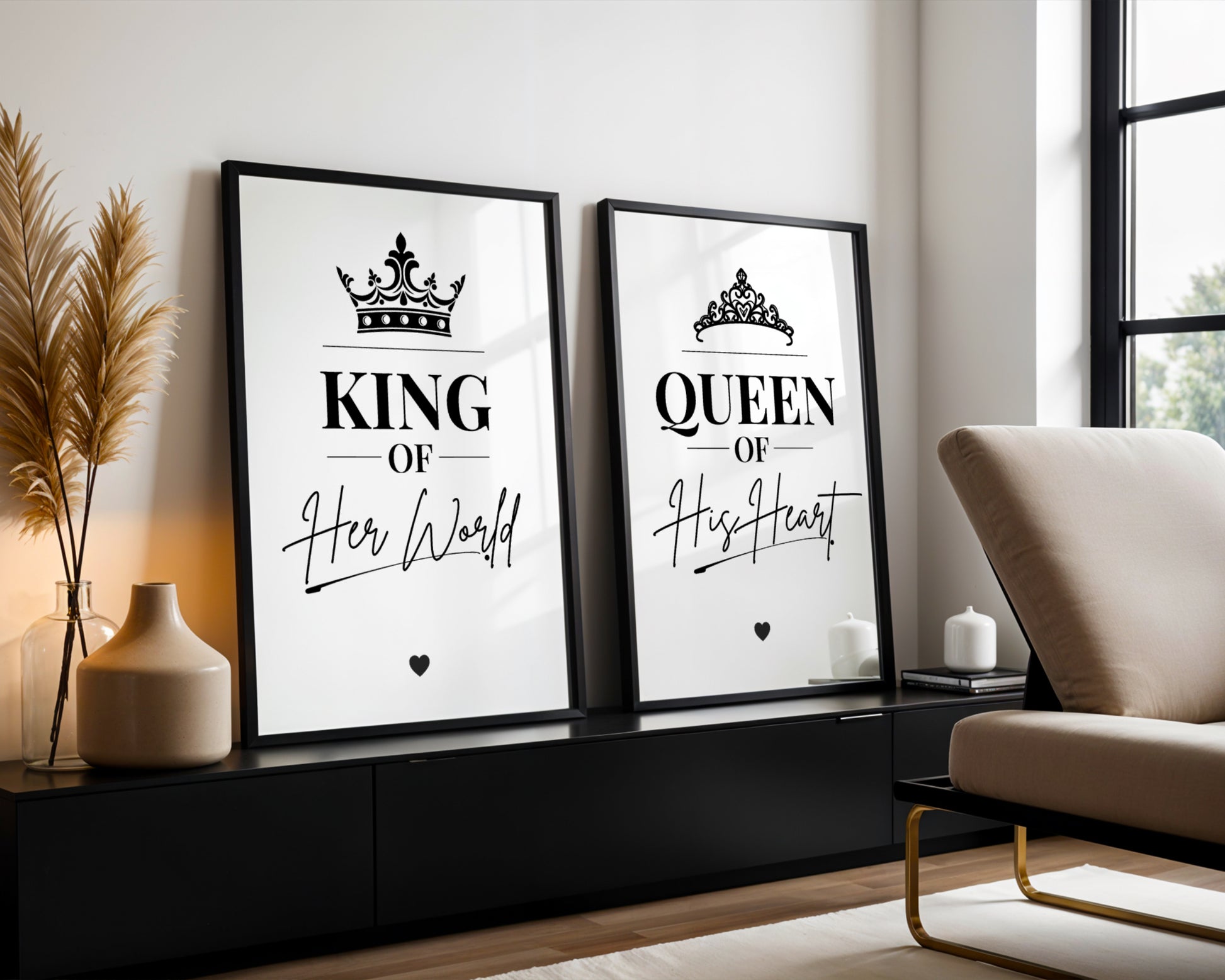 Two framed black-and-white wall art prints leaning against a light wall in a modern living room. The left print reads “KING Of Her World” with a crown graphic, and the right print reads “QUEEN Of His Heart” with a tiara graphic.