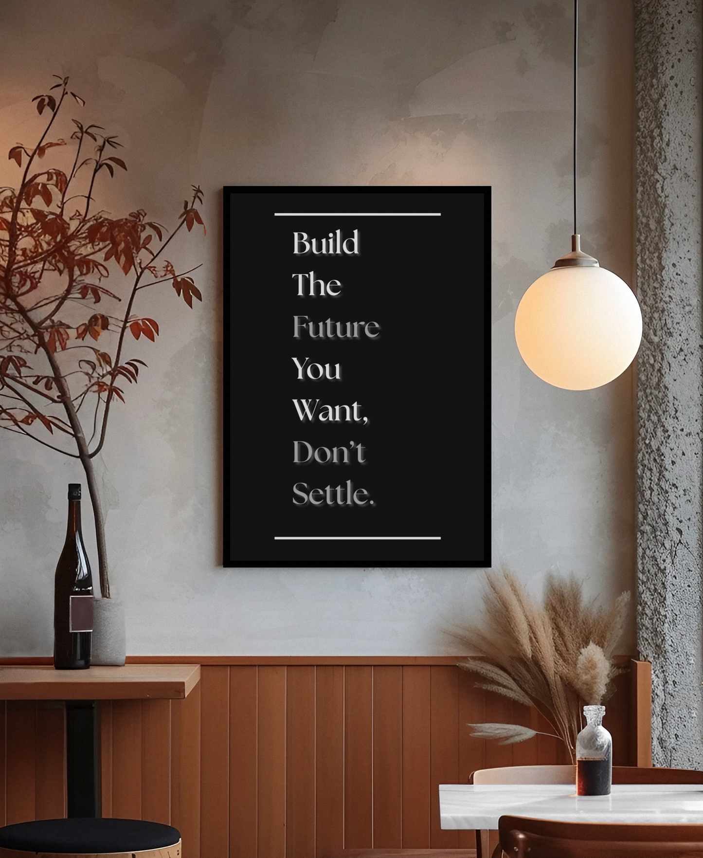 A framed black wall art print with white text reading a motivational quote, displayed in a modern interior setting with a hanging globe lamp, wood paneling, and decorative dried plants.