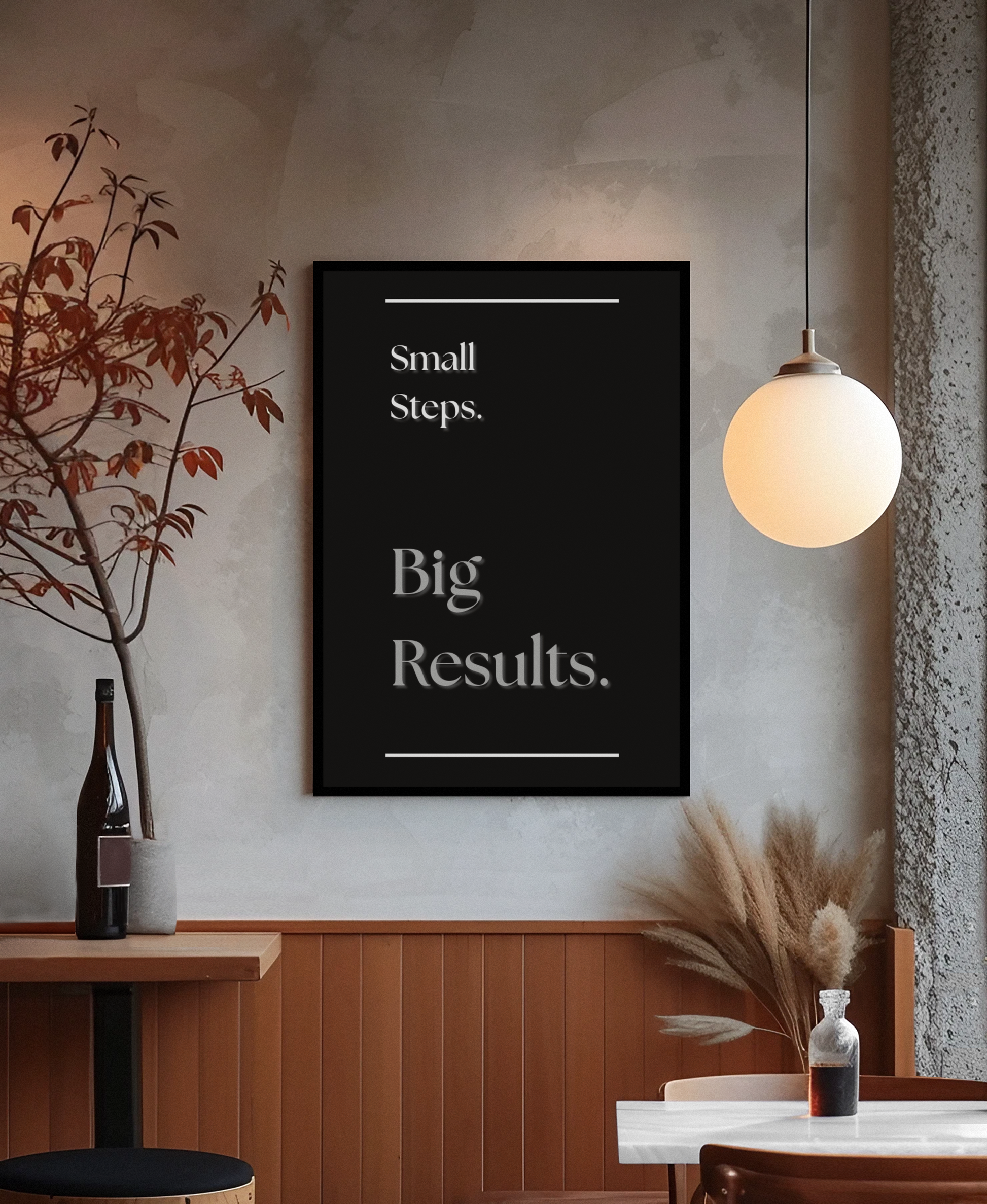 A black framed wall art print with white text reading 'Small Steps. Big Results.' displayed in a modern interior setting with a warm glowing pendant light, wood-paneled wall, and decorative dried grasses.