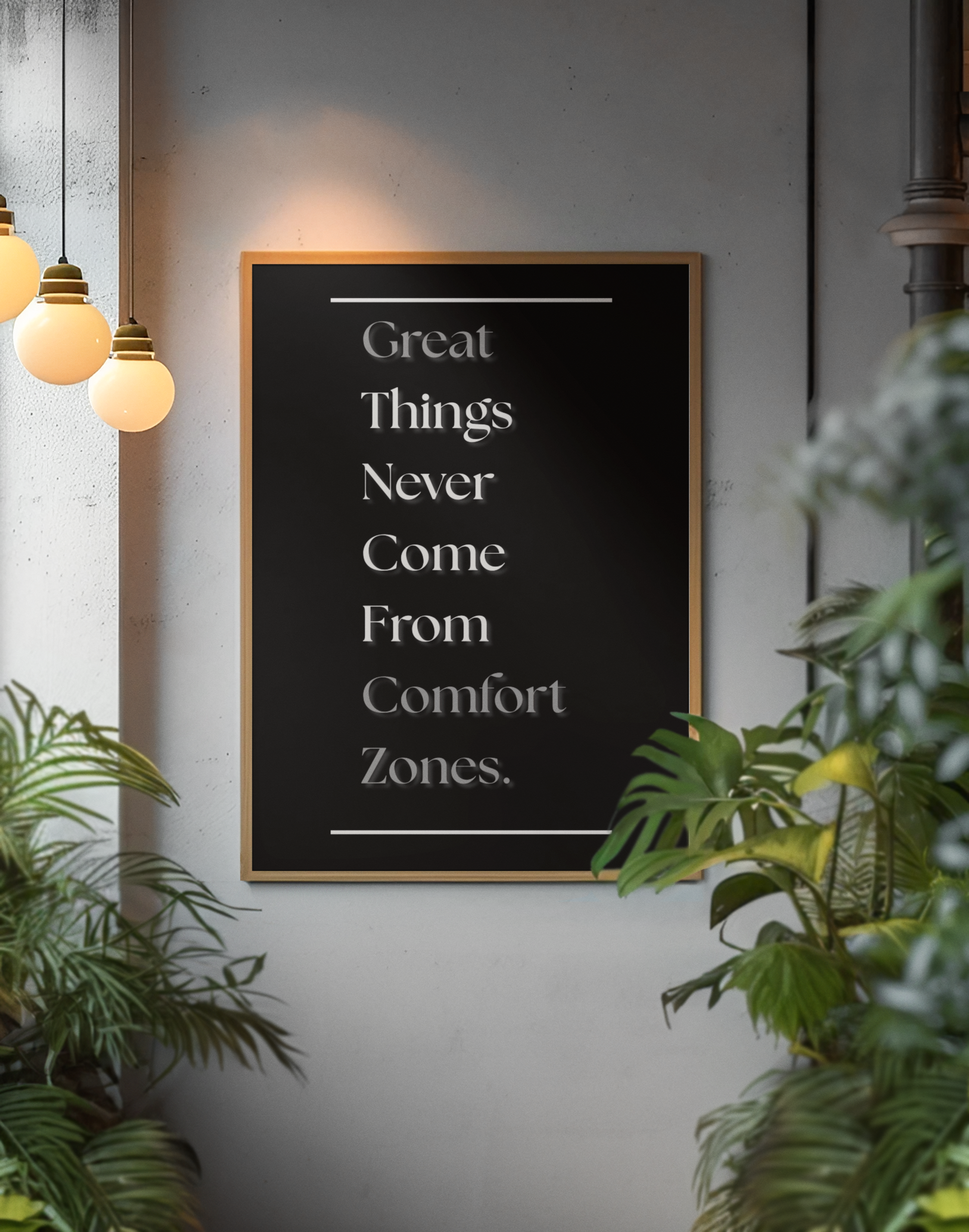 A framed typographic wall sign with the quote 'Great Things Never Come From Comfort Zones.' in white serif text on a black background, hanging on a gray wall in an indoor setting with hanging pendant lights and green plants around it.