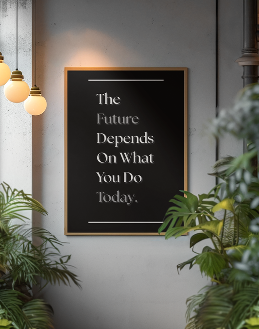 A framed typographic wall art print with a motivational quote in white text on a black background, hanging on a gray wall in a styled interior with hanging pendant lights and green plants.