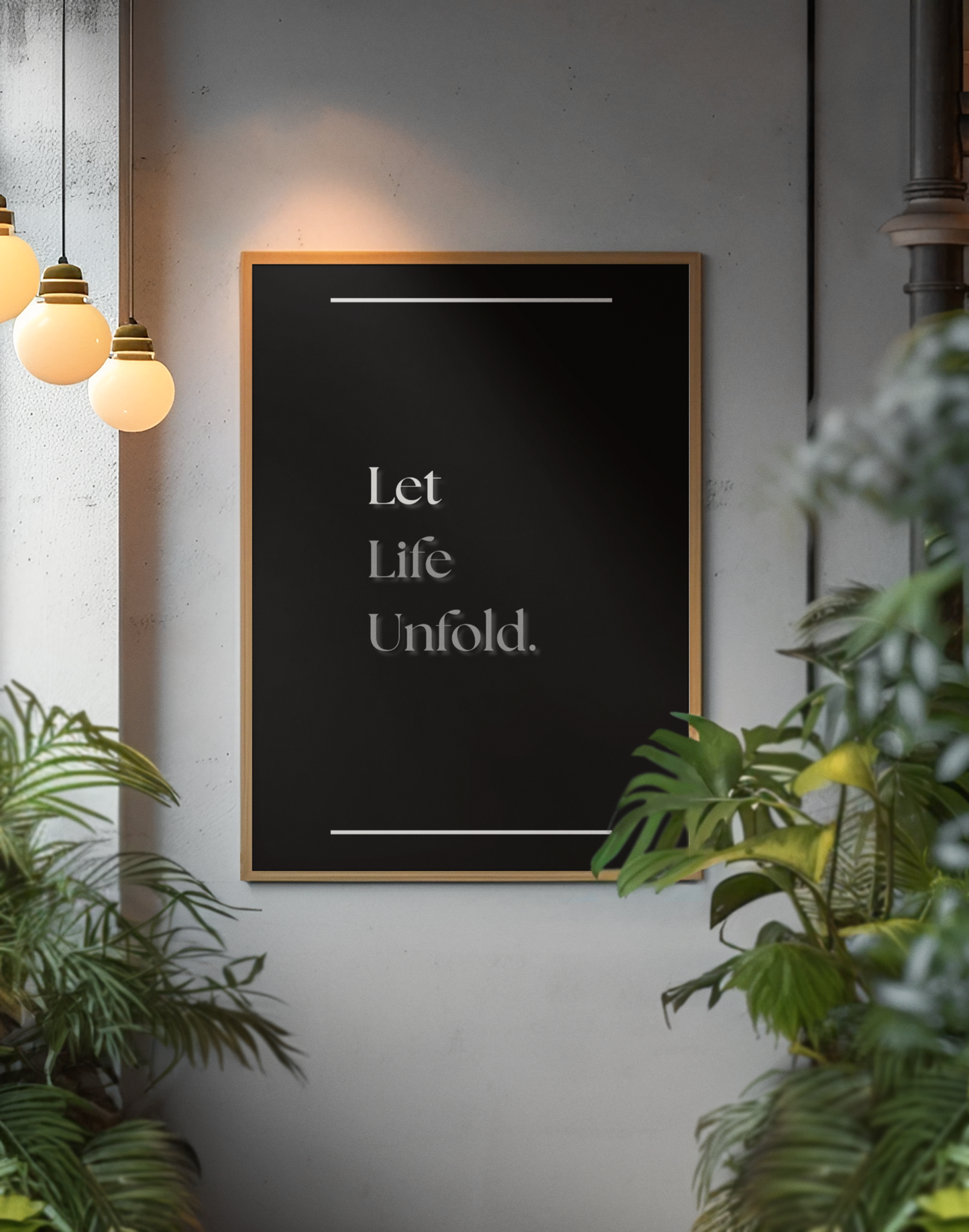 A framed wall art print with the quote 'Let Life Unfold.' in white serif text on a black background, hanging on a gray wall in a styled interior with hanging pendant lights and green plants.