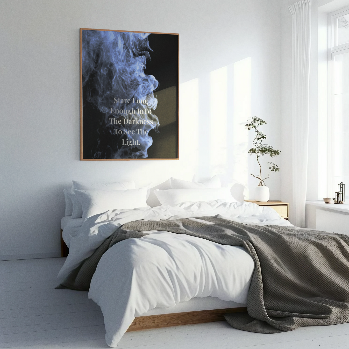 A framed wall art print featuring a dark smoky abstract design with the text 'Stare Enough InTo The Darkness To See The Light' displayed in a bright, modern bedroom setting.