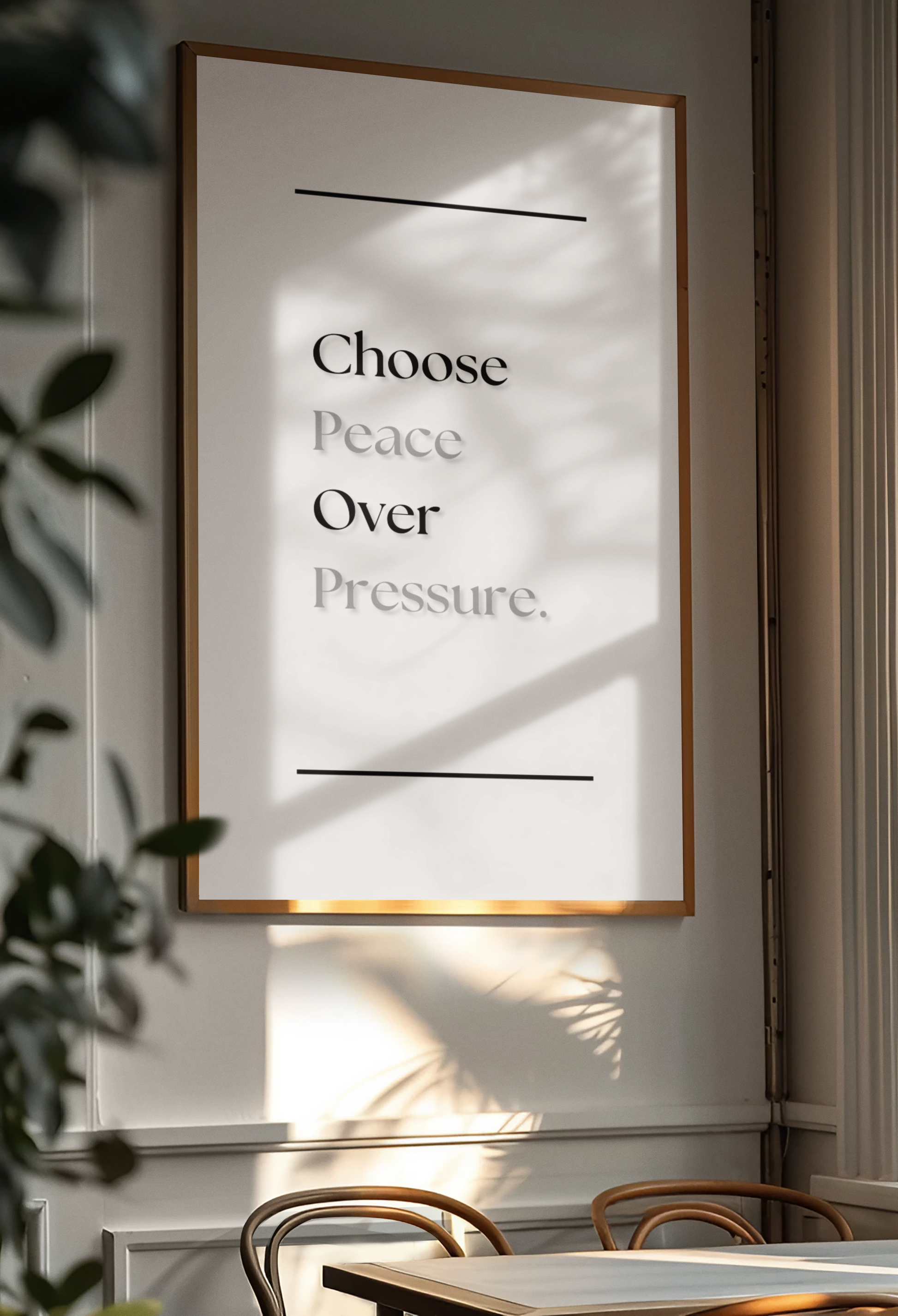 A framed wall art print with the quote 'Choose Peace Over Pressure.' hangs on a light gray wall in a dining or living space.