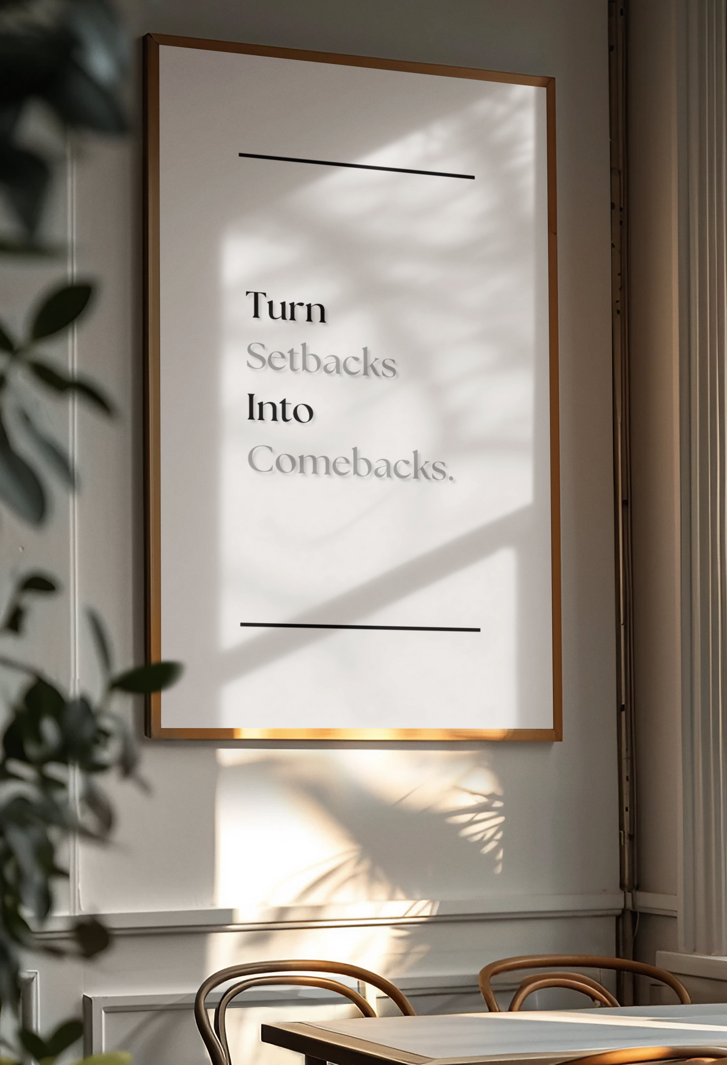 A framed minimalist art print with the text 'Turn Setbacks Into Comebacks.' hanging on a light gray wall in a dining room setting with natural window shadows.
