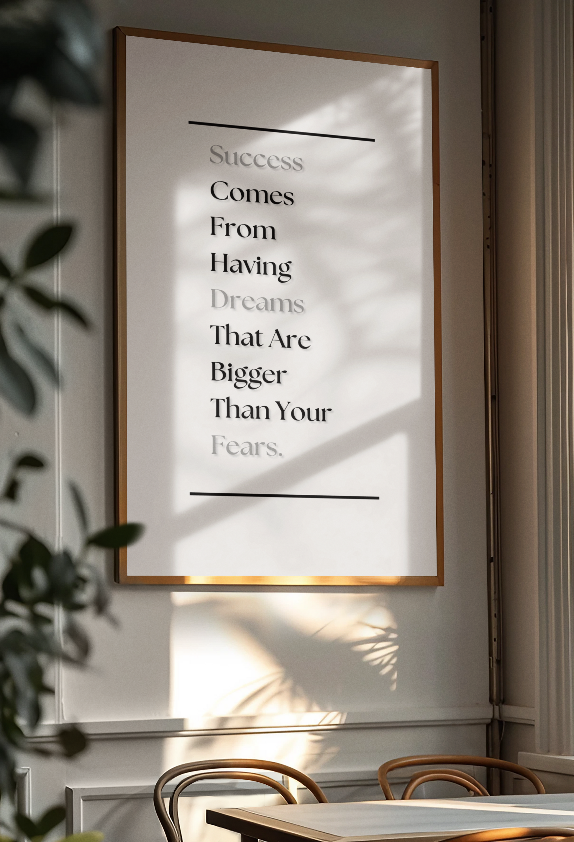 A framed motivational wall art print hanging on a light gray wall in a dining area. The print features a quote about success and dreams in black text on a white background, enclosed in a thin gold frame.