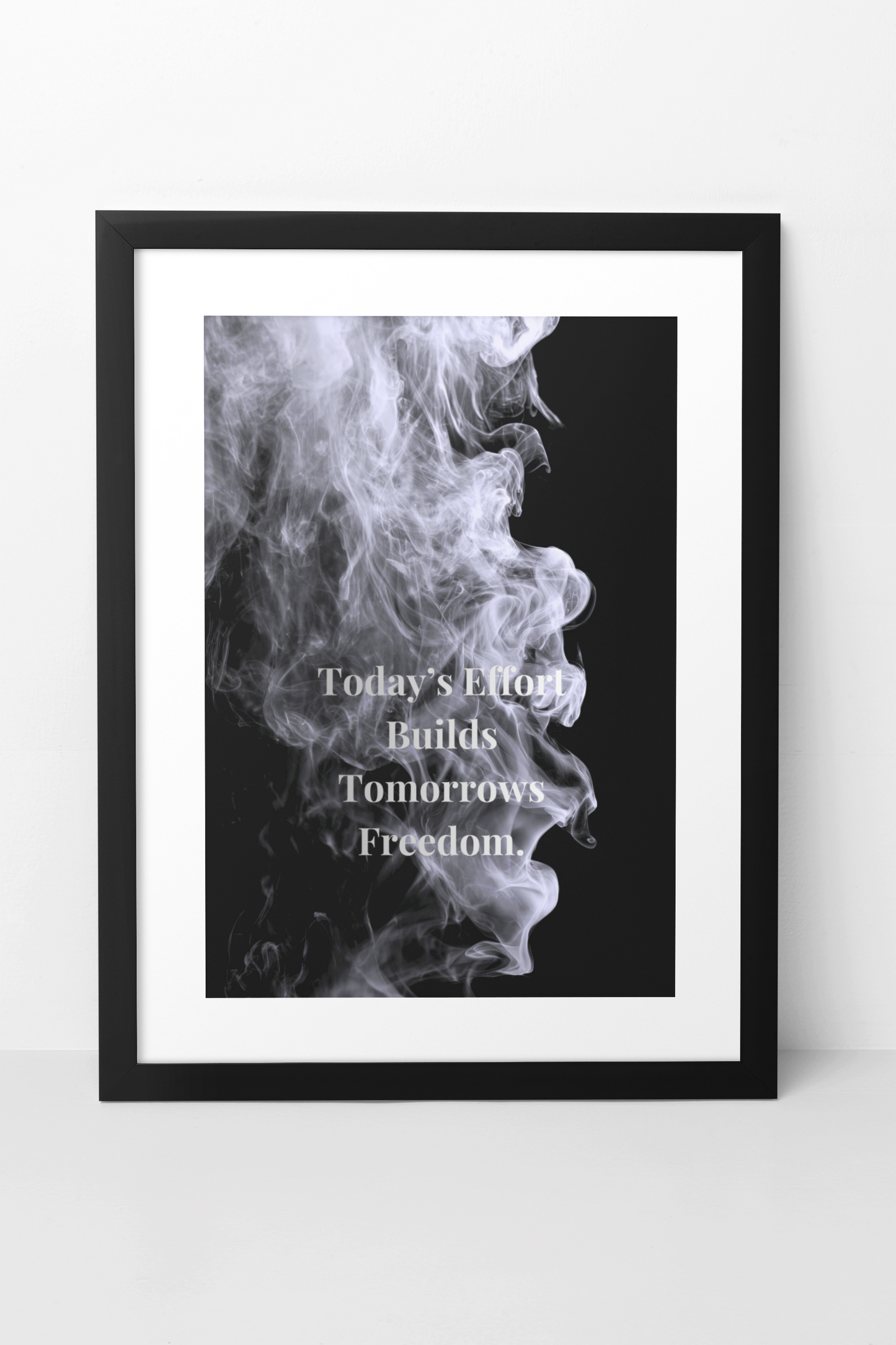 A framed wall art print featuring a black background with a white smoke profile and the text 'Today's Effort Builds Tomorrow's Freedom.' in white serif lettering.