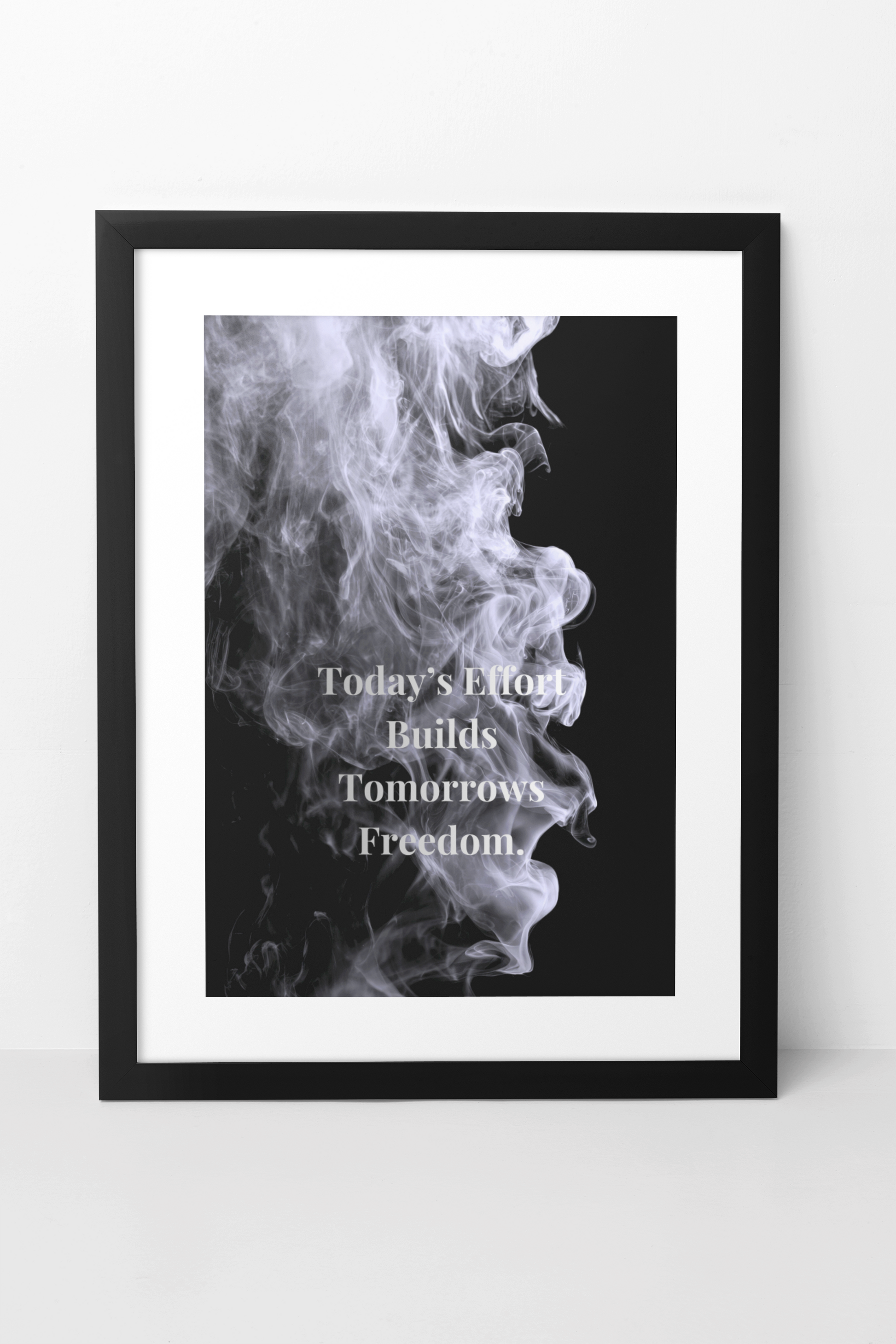 A framed wall art print featuring a black background with a white smoke profile and the text 'Today's Effort Builds Tomorrow's Freedom.' in white serif lettering.