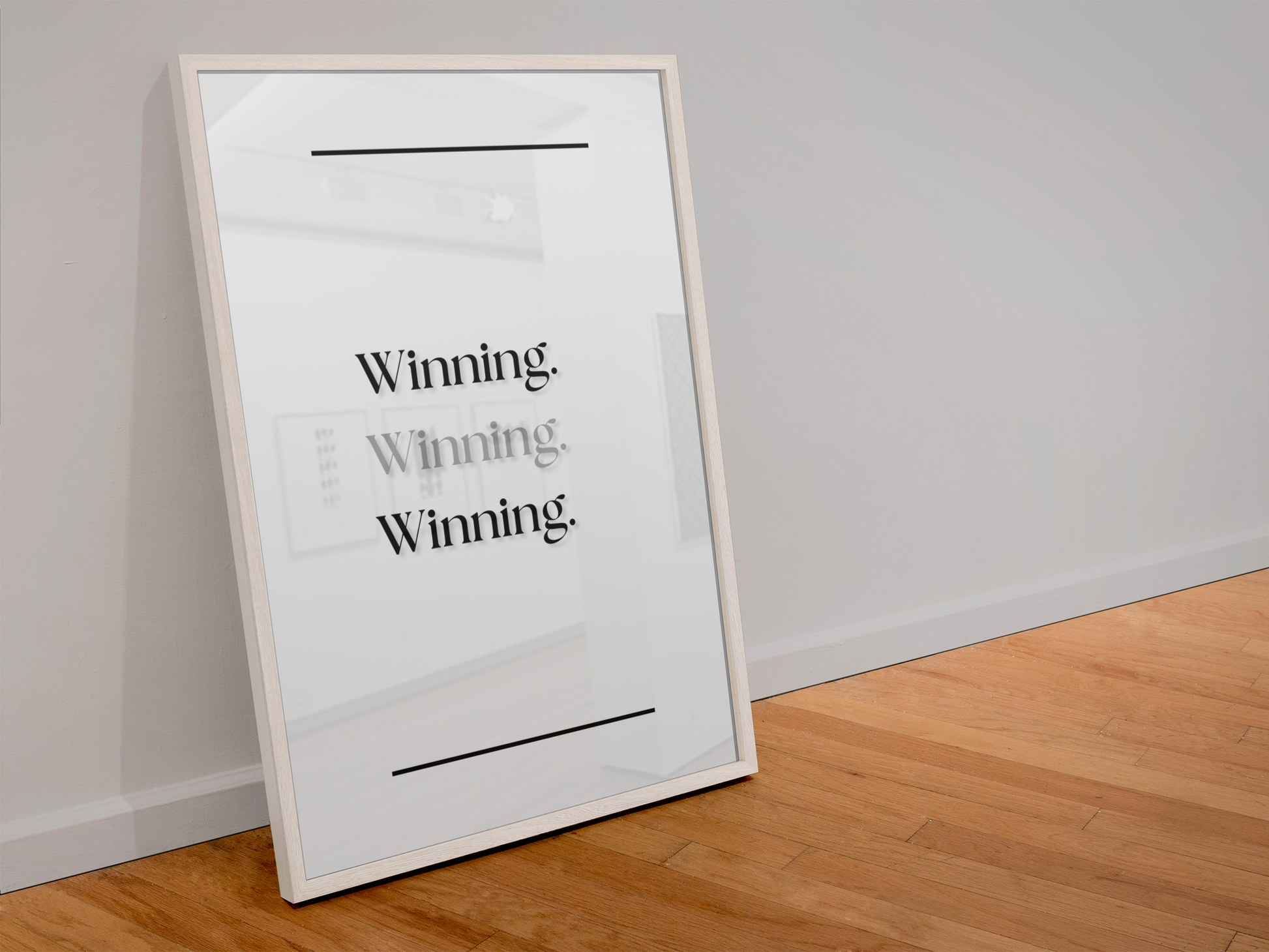 A framed typographic wall art print leaning against a light gray wall on a wood floor. The print has a white background with black text reading 'Winning Winning Winning'.