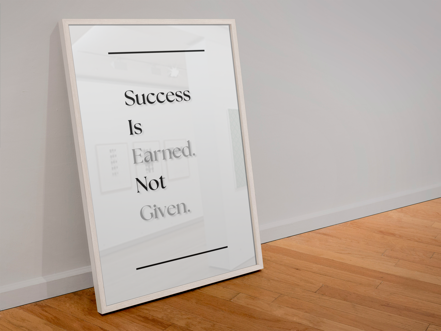 A framed motivational art print leaning against a white wall on a light wood floor. The print features the text 'Success Is Earned. Not Given.'