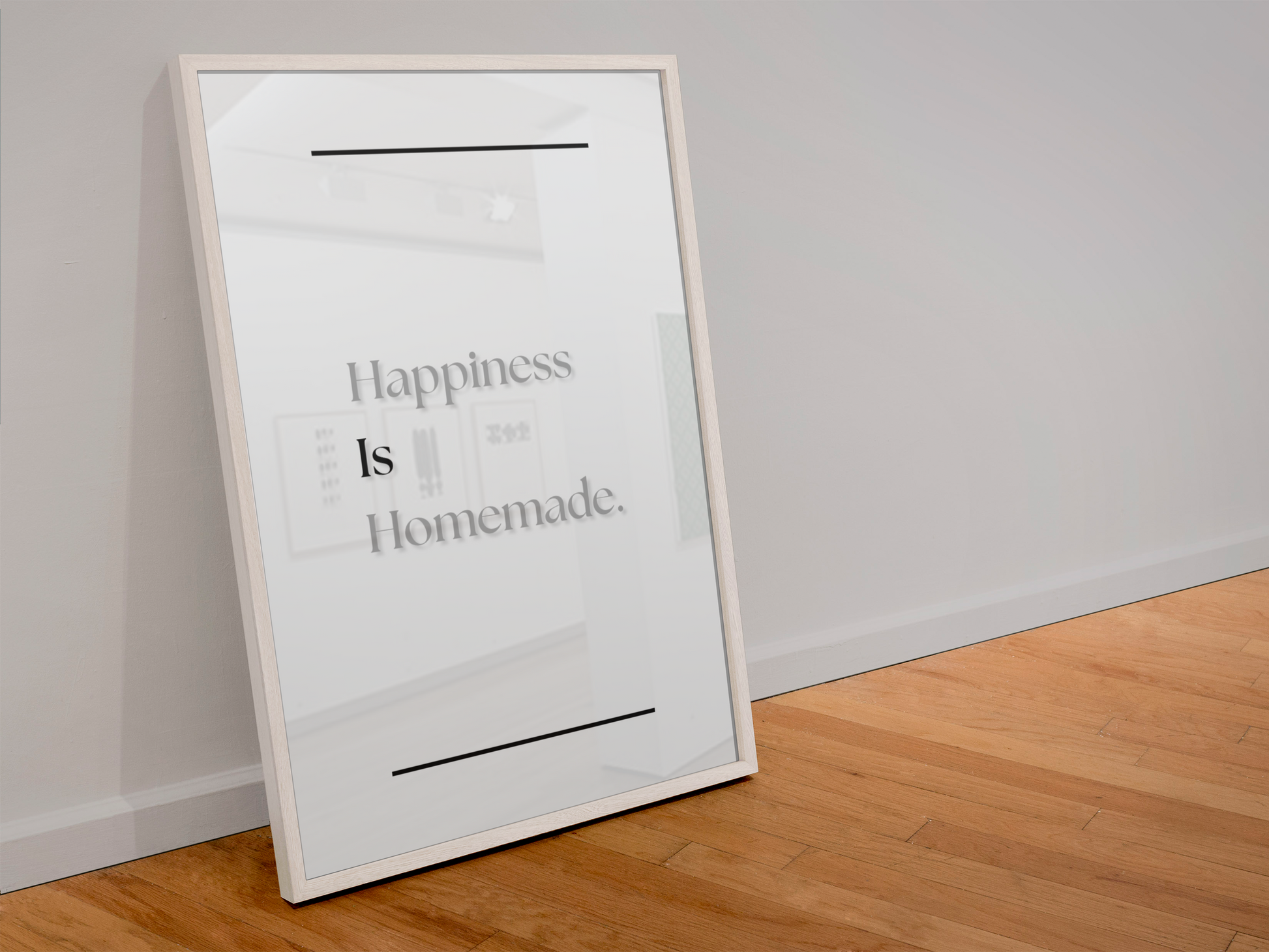 A framed minimalist art print leaning against a white wall on a light wood floor. The print features the text 'Happiness Is Homemade.