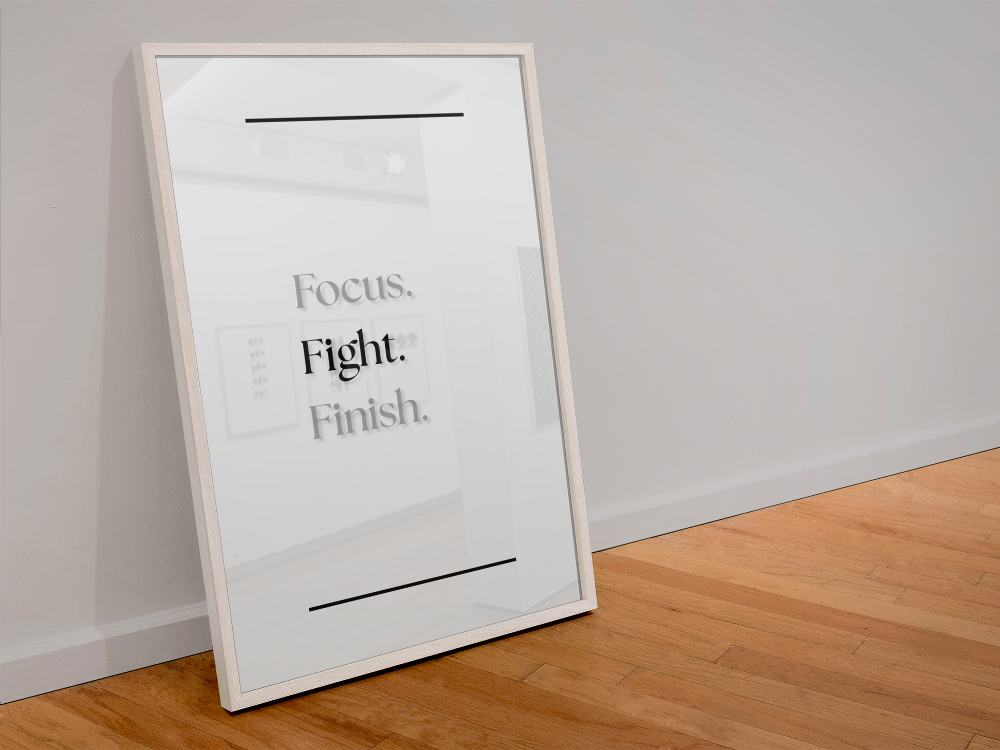 A framed motivational poster leaning against a light gray wall on a wooden floor. The poster features the text 'Focus. Fight. Finish.'