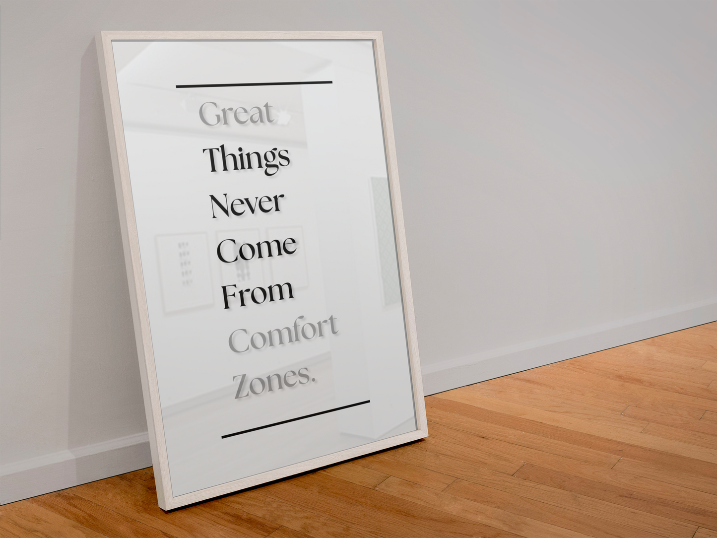 A framed motivational art print leaning against a white wall on a light wood floor. The print features the text 'Great Things Never Come From Comfort Zones'.