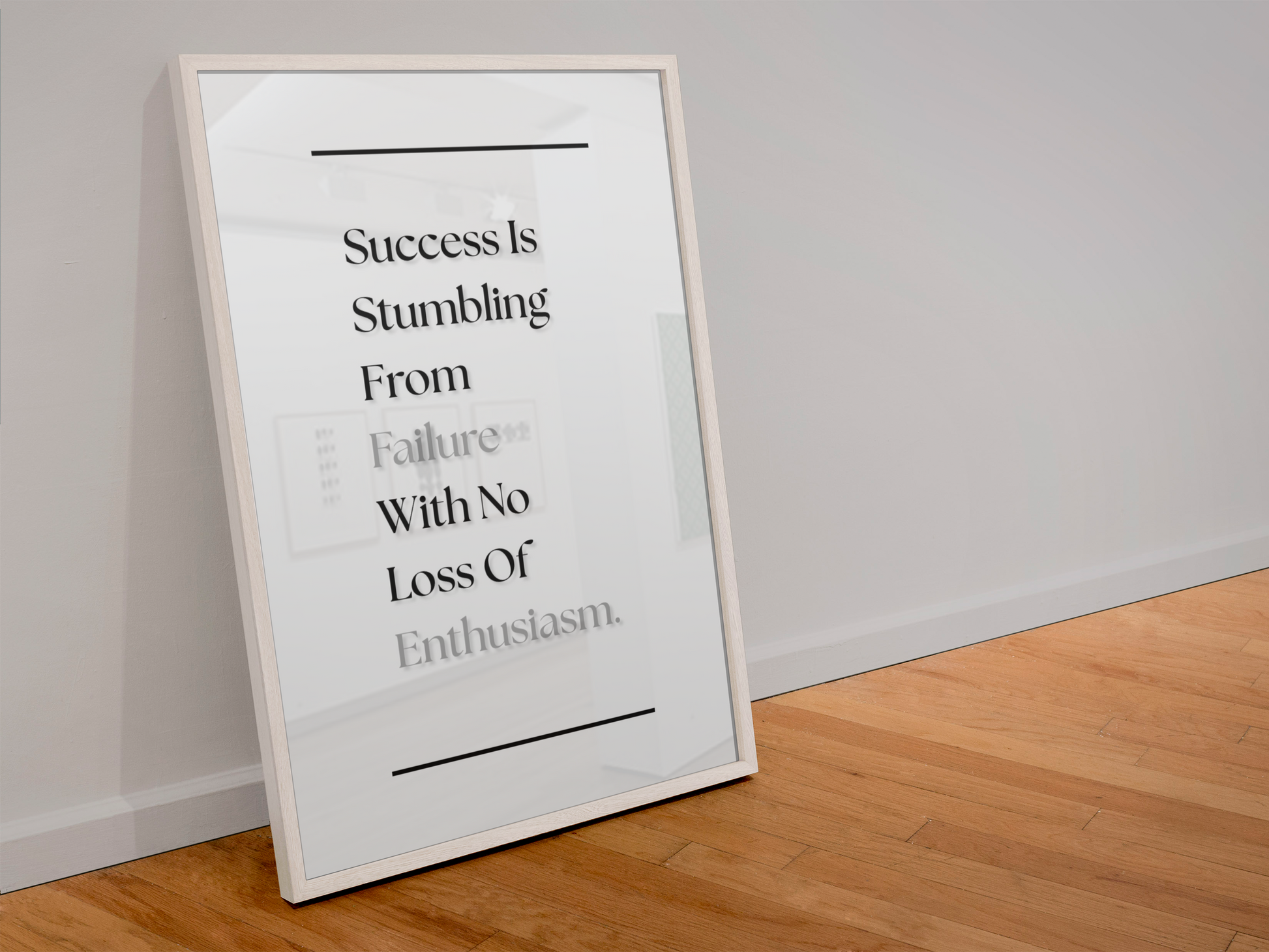 A framed motivational art print leaning against a white wall on a light wood floor. The print features a white background with black text that reads 'Success Is Stumbling From Failure With No Loss Of Enthusiasm'.