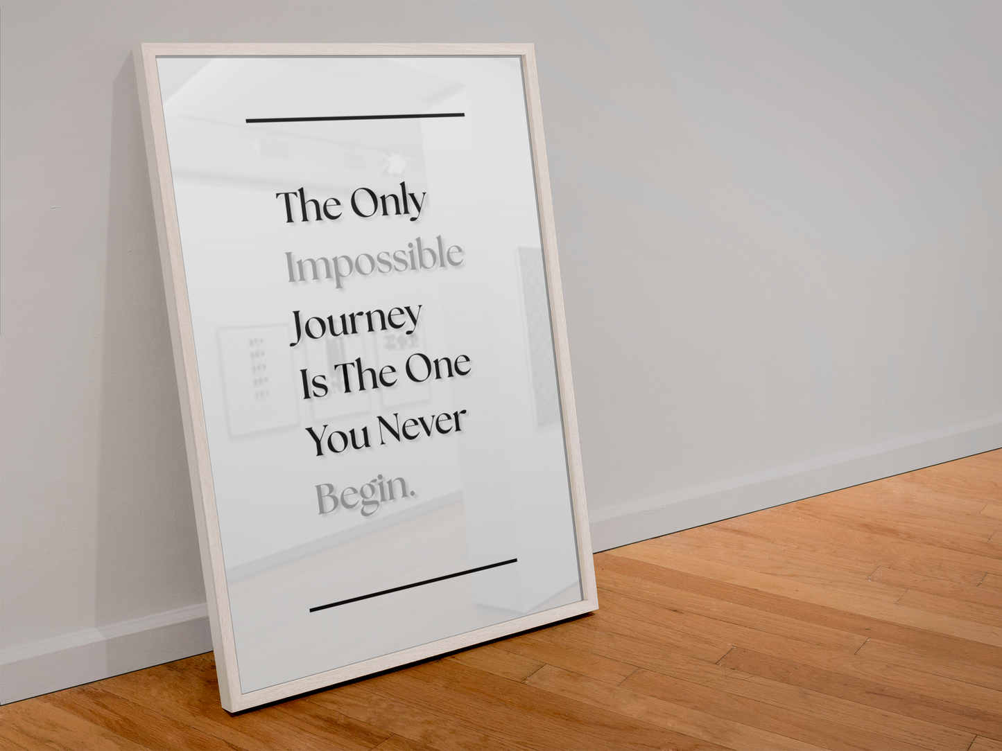 A framed typographic wall art print leaning against a white wall on a light wood floor. The print has a white background with black text reading, 'The Only Impossible Journey Is The One You Never Begin.