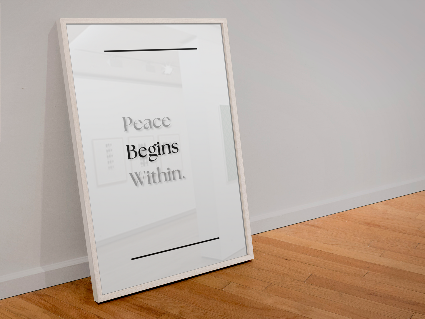 A large framed minimalist art print leaning against a light gray wall on a wooden floor. The print features the text 'Peace Begins Within.
