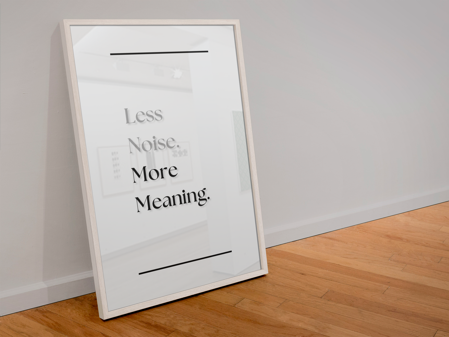 A framed minimalist art print leaning against a white wall on a light wood floor. The print features the text 'Less Noise. More Meaning'.