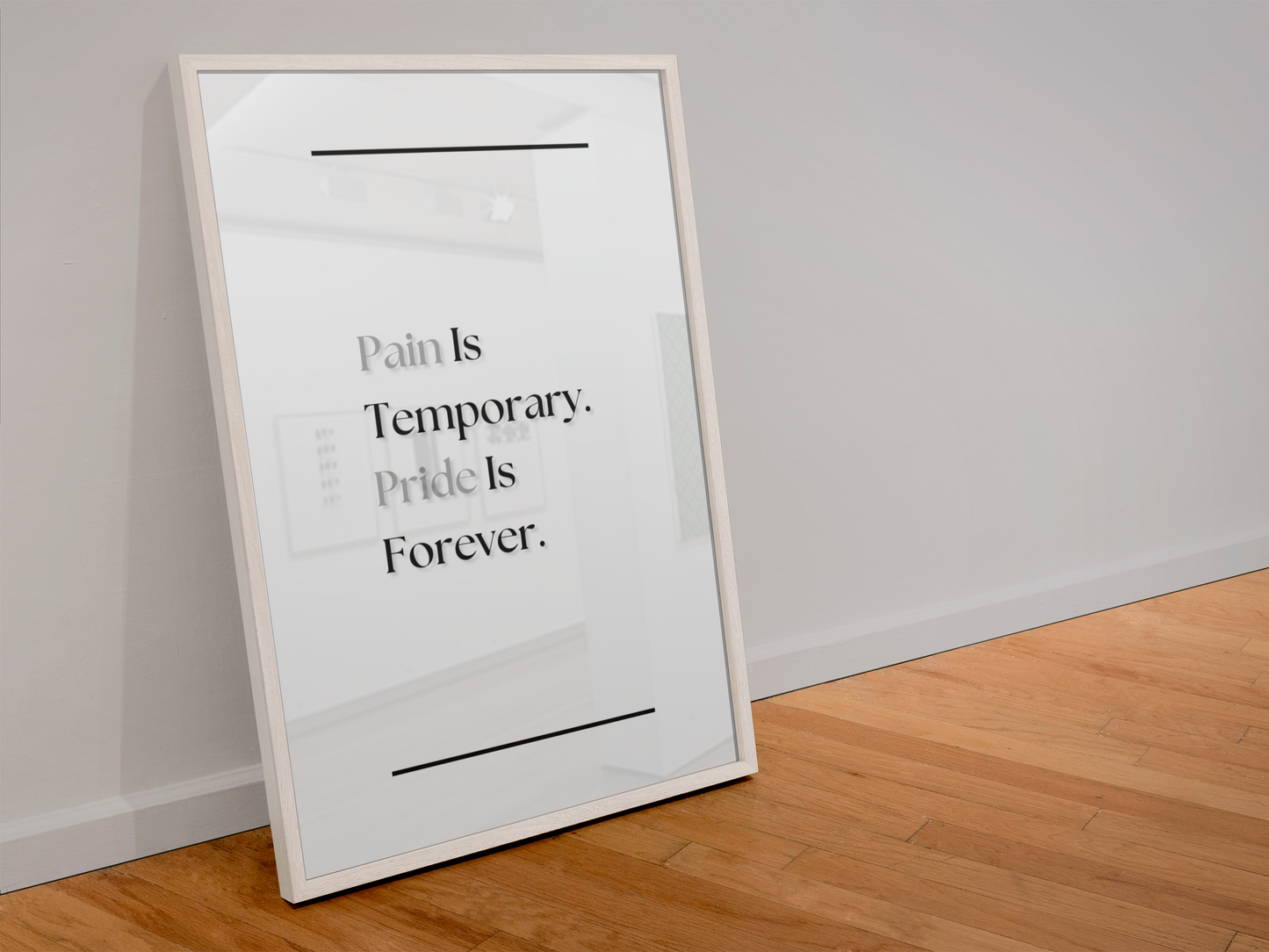 A framed motivational art print leaning against a white wall on a light wood floor. The print features the text 'Pain Is Temporary. Pride Is Forever'.