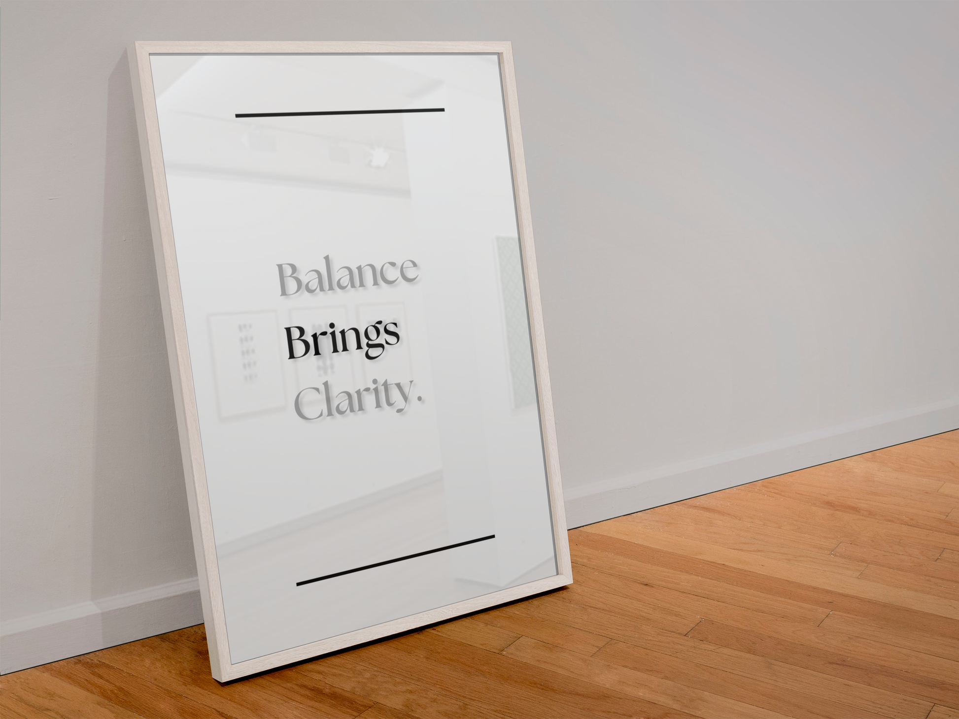 A framed minimalist art print leaning against a white wall on a light wood floor. The print features the text 'Balance Brings Clarity.