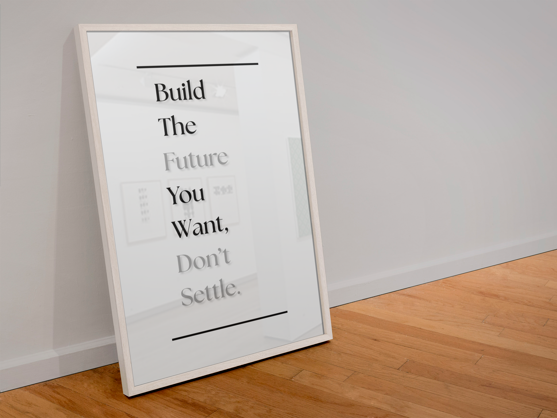 A framed typographic wall art print leaning against a white wall on a light wood floor. The print has a white background with black text reading, 'Build The Future You Want, Don't Settle.