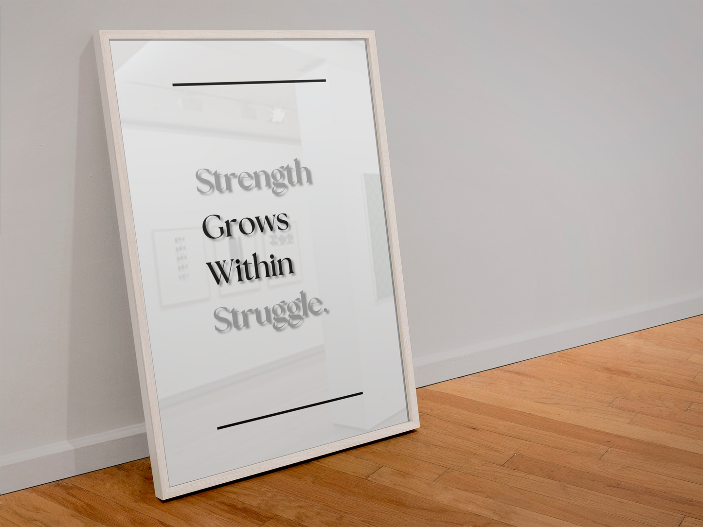 A framed motivational art print leaning against a white wall on a light wood floor. The print features the quote 'Strength Grows Within Struggle.'