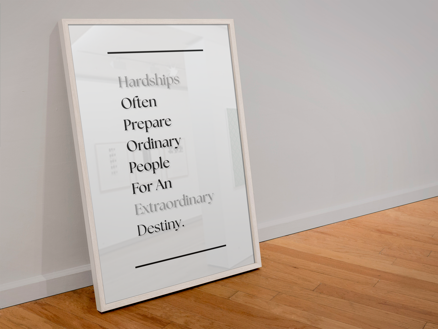 A framed motivational poster leaning against a white wall on a light wood floor. The poster features a quote about hardships and preparation in black and gray text on a white background, enclosed in a thin white frame.