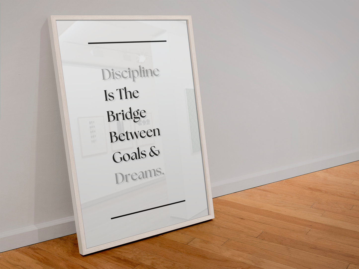 A framed typographic wall art print leaning against a white wall on a light wood floor. The print reads, 'Discipline Is The Bridge Between Goals & Dreams'.