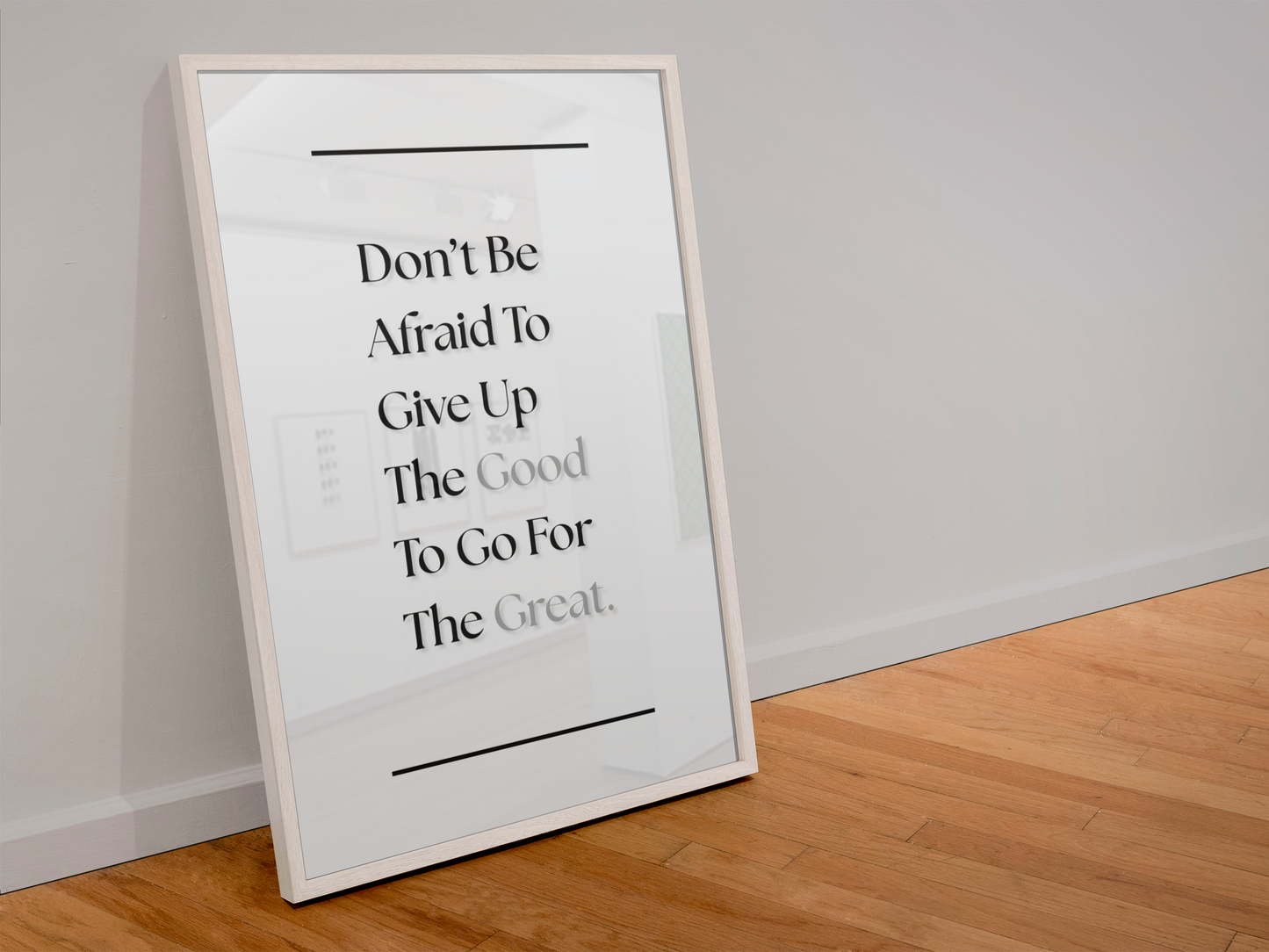A framed motivational quote print leaning against a white wall on a light wood floor. The print features black serif text reading 'Don't Be Afraid To Give Up The Good To Go For The Great.